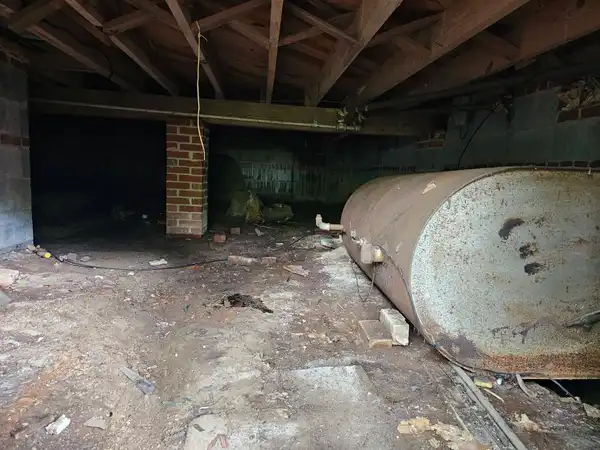 The same crawl space with bulky clutter removed and the tank still in place