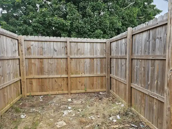 The same fenced corner with the pallets, boards and bags removed