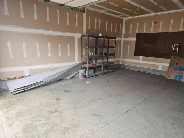 The same garage with the furniture and bins removed, leaving shelving and building materials
