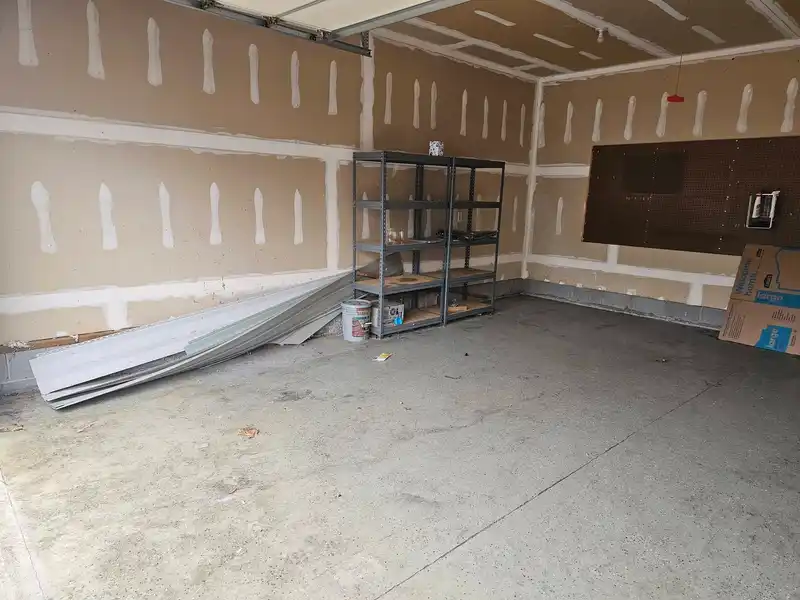 The same garage with the furniture and bins removed, leaving shelving and building materials