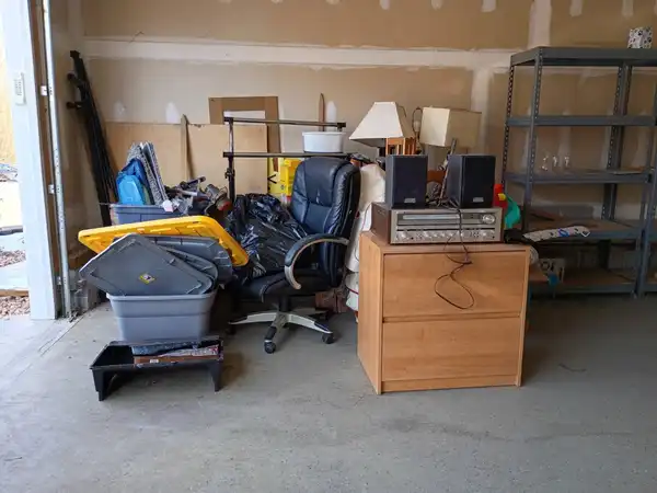 Furniture, storage bins and an office chair gathered in a garage