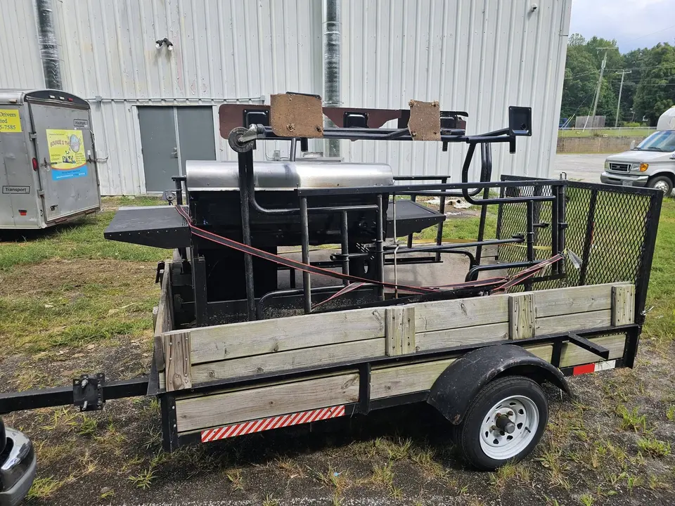 A large grill and metal frames loaded into a utility trailer