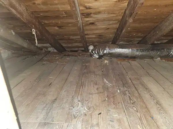 The same low attic with the debris removed and floorboards visible