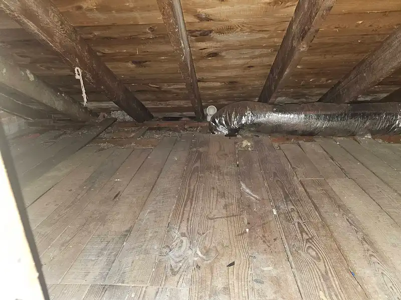 The same low attic with the debris removed and floorboards visible