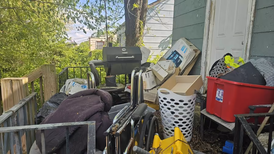 Household items, a grill and containers gathered on a porch