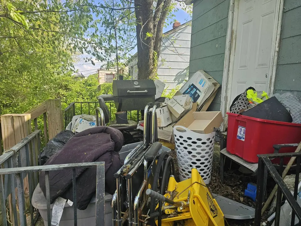 Furniture, a grill, bins and household items gathered on a porch