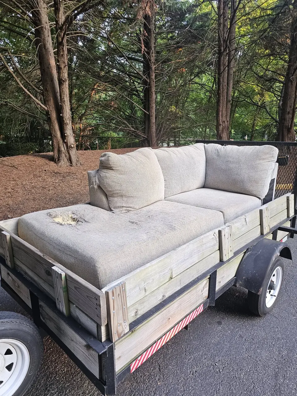 A gray sectional sofa loaded into a utility trailer