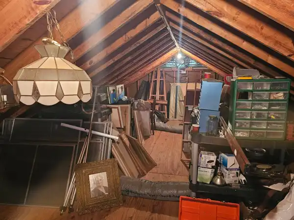 Furniture, boards and loose items filling the aisle of a walk-in attic