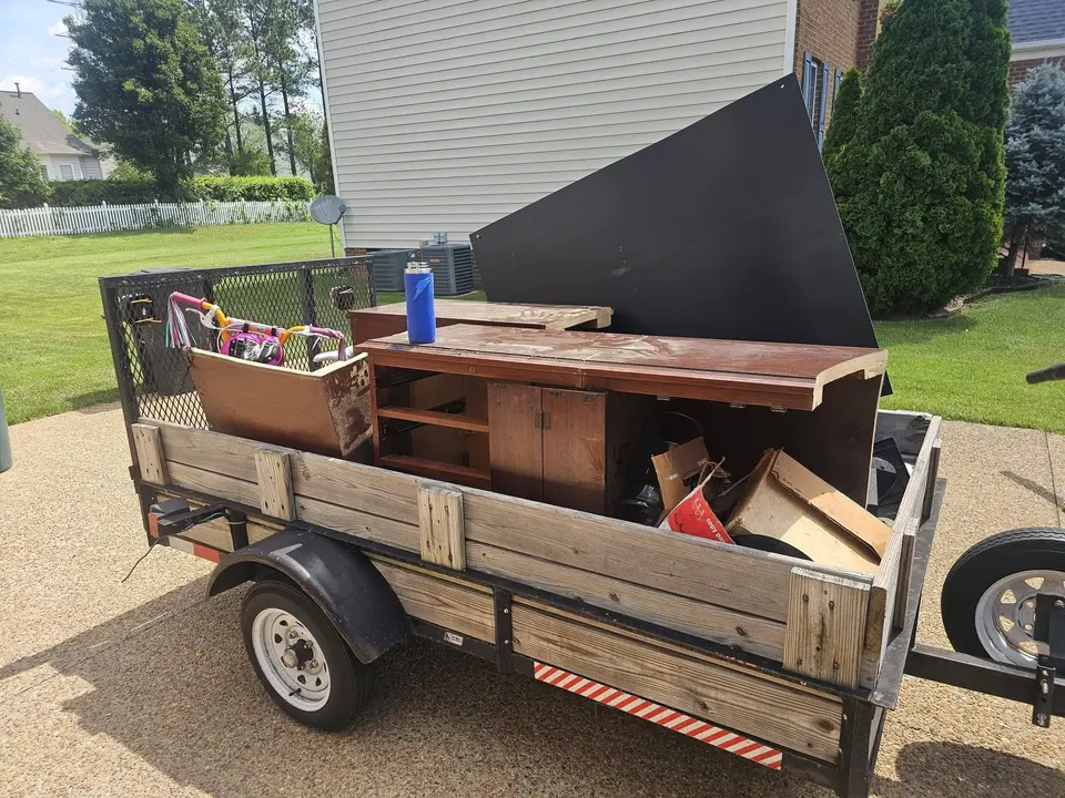 Wooden furniture, shelving and a dark panel loaded into a utility trailer